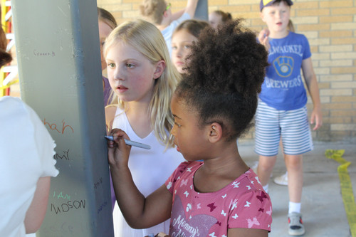 Adults and kids drawing on a structural pillar inside a building