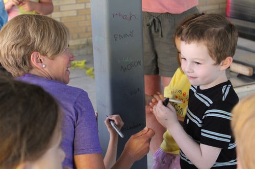 Adults and kids drawing on a structural pillar inside a building