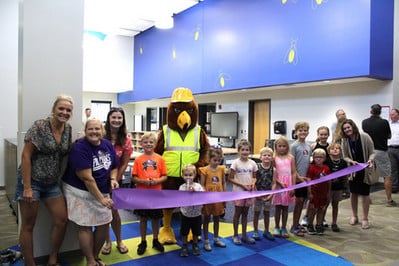group of people cutting a larger ribbon